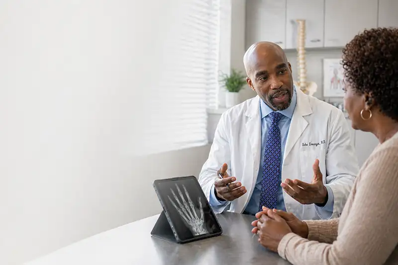 Dr. Uche Eneanya speaking with patient during pain management consultation