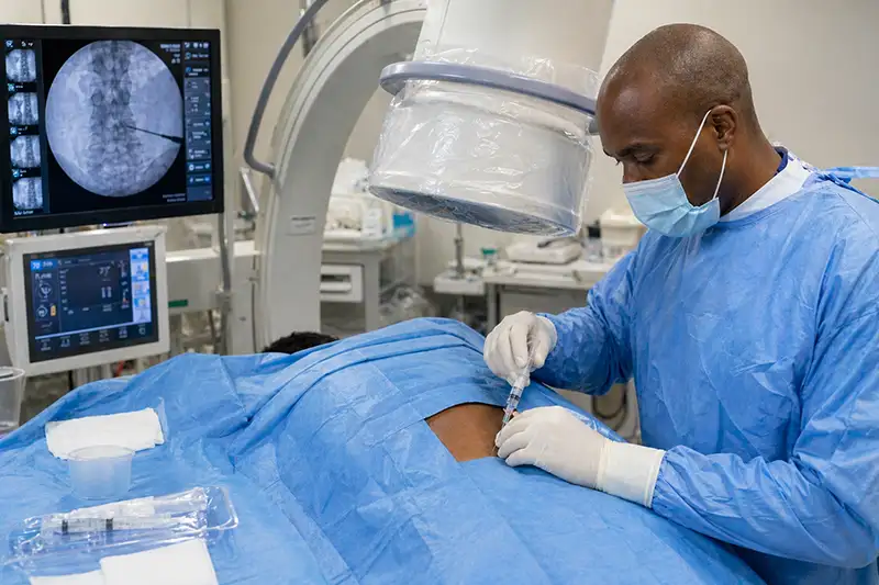 Dr. Uche Eneanya performing fluoroscopy-guided spinal injection procedure on patient