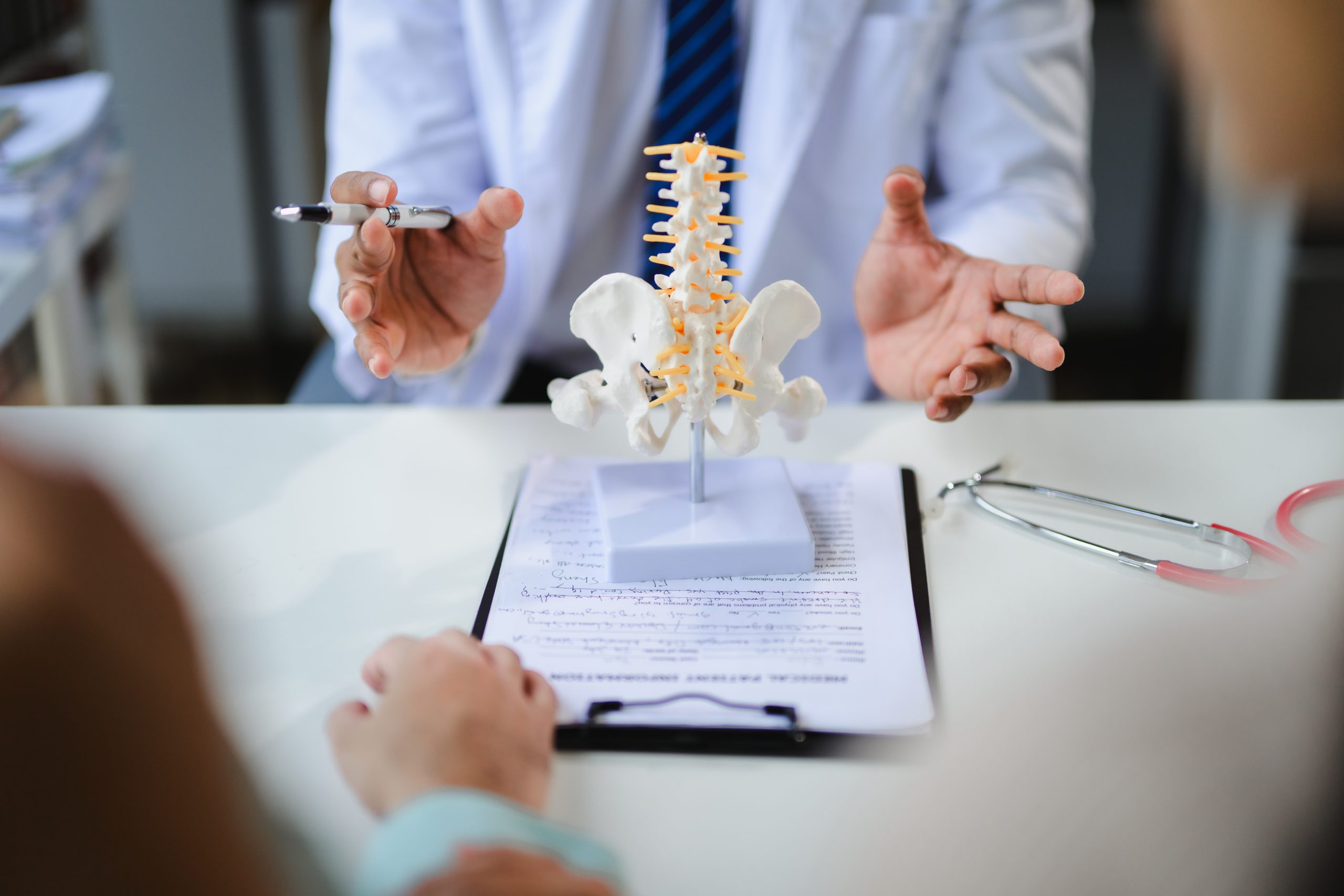 a pain doctor explaining sciatic nerve pain and radiculopathy to patient using spine model