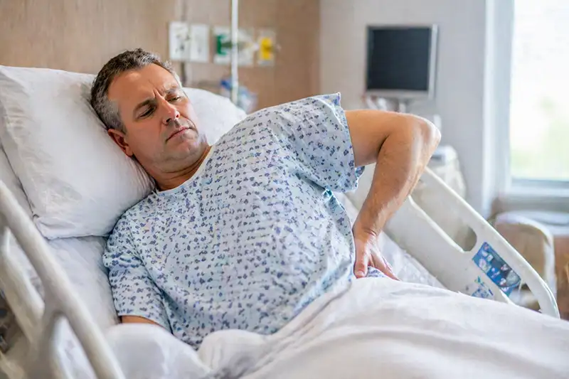 Patient lying in hospital bed experiencing ongoing back pain after spine surgery