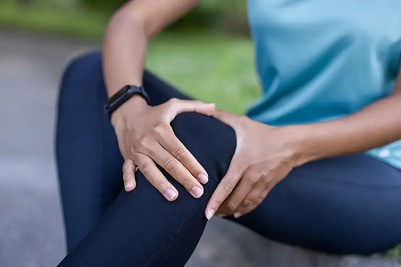 Person holding knee and leg in pain, illustrating sciatica symptoms and nerve pain