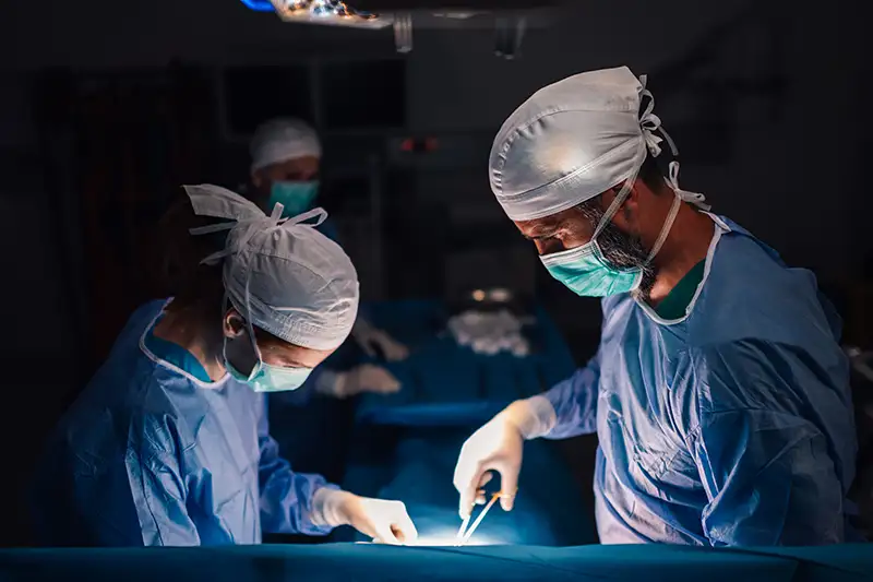 Surgical team performing minimally invasive spine procedure under operating lights