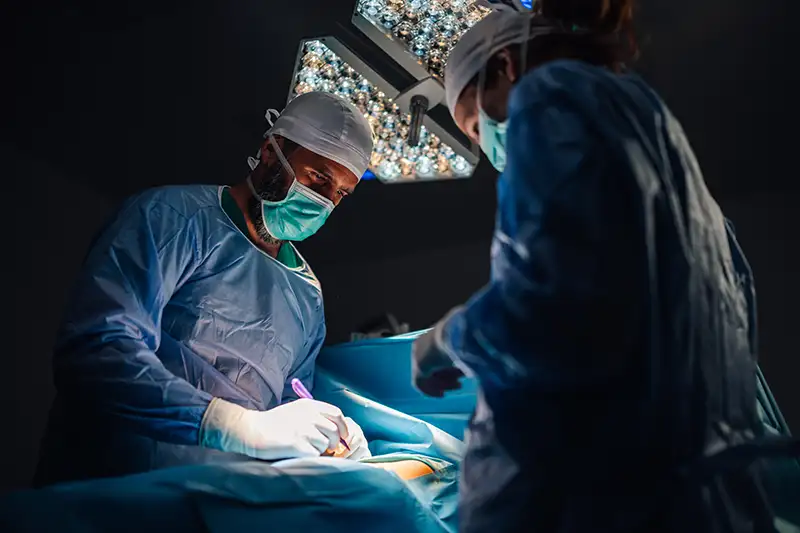 Surgical team performing spine surgery under operating lights