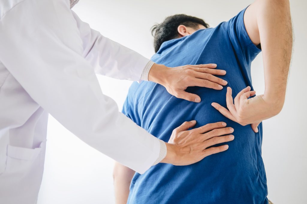 Male patient showing doctor where the pain is that can be treated with non-surgical pain management tactics like injections