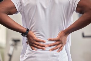 Man holding his lower back in pain, a symptom that may occur with a bulging or herniated disc.