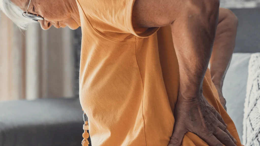 Adult holding lower back in pain, a common sign it may be time to consider spine surgery evaluation.