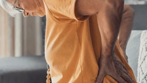 Adult holding lower back in pain, a common sign it may be time to consider spine surgery evaluation.