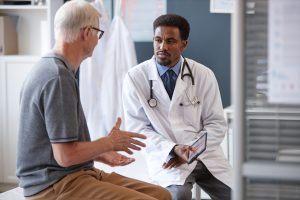 Doctor listening to an older male patient during a spine surgery consultation.